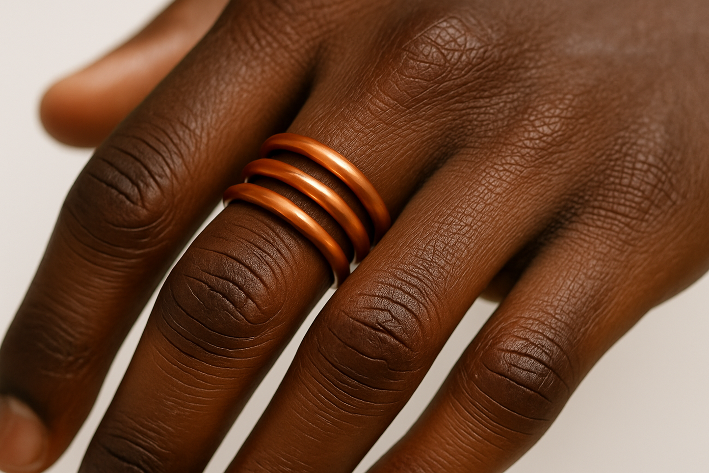 a black man's hand wearing a simple 3 coil copper ring